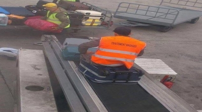 صورة : عامل في مطار تونس قرطاج يجلس على امتعة المسافر