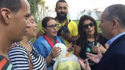صورة : الصحفية سهام عمار تحمل ابنها الرضيع اثناء عملها 